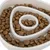 Close-up of a white anti-gulp bowl with brown dry food pieces, spiral structure for slow feeding.