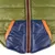 Detailansicht einer olivgrünen Steppjacke mit dunkelblauen Taschen und orangefarbenen Akzenten sowie einem Reissverschluss in der Mitte.