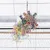 Jouet suspendu en osier avec bandes colorées et lamelles de papier multicolores, accroché à une cage par une chaîne métallique.