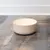 Beige Futternapf aus Keramik auf Holzoberfläche, geeignet für Haustierfutter oder Wasser.