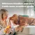 Texte : Délicieuses friandises pour chien à faible teneur en matières grasses. Femme tenant un paquet de friandises Pedigree devant un chien assis sur un canapé.