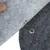 Gros plan sur deux pièces de feutre gris clair et foncé avec bouton-pression métallique visible, montrant le système d’attache du produit.