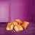 Image showing several crunchy, filled snack pieces with a golden-brown exterior and creamy filling, displayed on a purple surface.