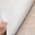 Nahaufnahme eines Teppichs mit strukturierter Oberfläche und rutschfester Unterseite, die von einer Hand angehoben wird.