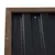 Détail d’un panneau avec cadre en bois et surface ondulée noire fixée par des vis, matériaux visibles : bois et métal.