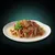 Chunks of meat in gravy with visible red vegetable pieces, served on a white plate and garnished with parsley.