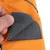 Gros plan sur une fermeture à scratch en tissu gris sur un vêtement orange, montrant la texture du velcro et la couture visible.