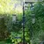 Vogelfutterstation mit drei hängenden Futterspendern für Samen und Körner, sowie einer Plattform für zusätzliche Fütterung. Metallgestell in einem Gartenbereich.