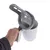 Mano sostiene vaso medidor blanco con asa gris y tapa colador, apto para dosificar alimento para mascotas u otros materiales.