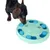 Dog examines green and blue interactive toy with compartments for treats.