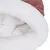 Vue rapprochée d’un couchage pour animal en tissu blanc duveteux à intérieur et rebord extérieur en tissu côtelé rose.