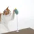 Spielzeug mit Federmechanismus und grünem Stofftier, befestigt auf einer Kratzmatte. Katze interagiert mit dem Spielzeug.