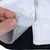 Primo piano di una chiusura in velcro bianca su tessuto grigio, aperta da una mano.
