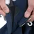 Close-up van een blauwe klittenbandsluiting en metalen haak die door een hand wordt geopend. Toont de werking van het sluitsysteem.