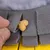Una mano mette un piccolo biscotto per cani in una borsa di stoffa grigia, parte di un gioco interattivo per la ricerca di snack.