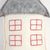 Dekoratives Kissen in Form eines Hauses mit grauem Dach und roten gestickten Fenstern auf weißem Stoff.