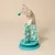 Chat beige jouant avec un arbre à jouets interactif en plastique turquoise, équipé de balles et d’un pompon suspendu. Jouet en forme de sapin sur socle rond.