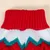 Nahaufnahme eines gestrickten roten Kragens mit weissem und türkisfarbenem Zickzackmuster darunter.