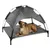Dog lying on elevated grey pet bed with integrated sunshade roof. Product shows a combination of comfort and protection for pets.