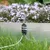 Elektrischer Anschluss an einem Metallrahmen, umgeben von Gras und Blumen. Kabel führt vom Anschluss weg.