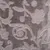 Motif floral en relief sur tissu doux, couleur gris taupe. Texture velours visible, sans autres éléments distinctifs.