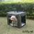 Chien dans une caisse de transport en tissu gris avec poignées, posée sur l’herbe. Texte visible : Größe M.