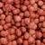 Croquetas de pienso seco de color marrón rojizo, forma redonda y superficie rugosa, agrupadas en primer plano. No se muestra marca ni información adicional.