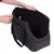 Sac de transport noir pour animaux, avec bandoulière réglable, poche zippée sur le côté et intérieur rembourré. Deux mains tiennent le sac ouvert.