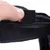 Gros plan sur une main ouvrant une fermeture à scratch en tissu noir, montrant le système de fixation du produit.