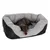 Graues Hundebett mit schwarzen Seiten, ein kleiner brauner Hund liegt darin.