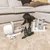 Black dog on carpet next to a set of grooming tools, brushes, clipper, two green spray bottles and a white vacuum device.