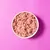 Bowl filled with minced, raw pet food on a pink background.