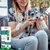 Vrouw brengt Vet's Best Dental Gel aan op de tanden van een hond. Verpakking toont tandverzorgingsset met gel en borstel.