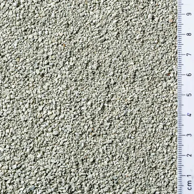 Närbild av grått granulat med centimeter-skala, visar materialets kornstorlek.