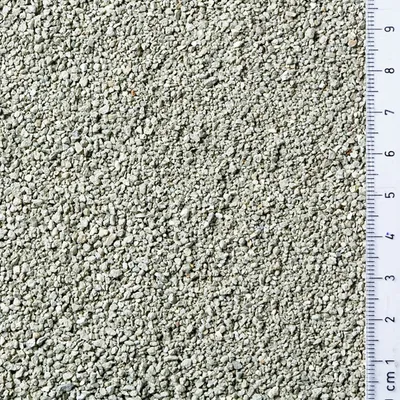 Close-up of light grey granules with a ruler showing particle size from 1 to 9 centimetres for scale.