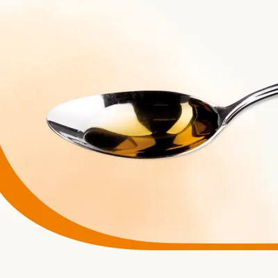 A metal spoon filled with golden liquid, shown close up to illustrate product texture or serving suggestion.