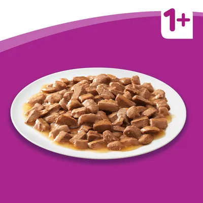 Szószban tálalt húsos falatok fehér tányéron, lila háttéren. Sarokban „1+” felirat látható.