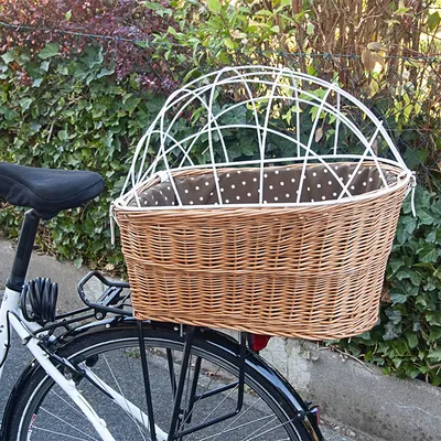 Panier en osier avec grille métallique blanche et doublure à pois, fixé sur le porte-bagages arrière d’un vélo. Matériaux visibles : osier, métal, tissu.