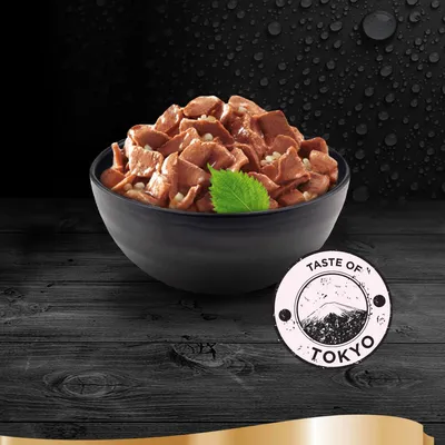 Kulhollinen ruskeaa palaruokaa, koristeena vihreä lehti. Edessä pyöreä merkki: Taste of Tokyo, jossa vuorikuva.