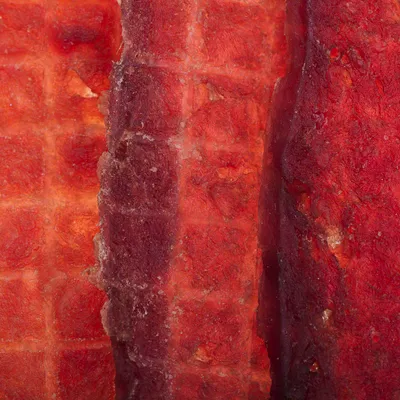 Close-up of red, dried meat strips with a textured surface.