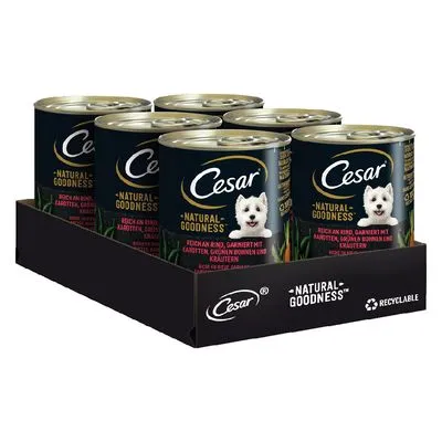 Multipack Cesar Natural Goodness hondenvoerblikken, zichtbaar merk en tekst: 'Natural Goodness', afbeelding van witte hond op elk blik, verpakking met recyclebaar-symbool.