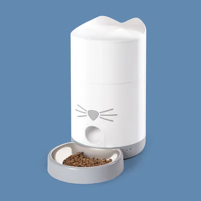 Weisser Futterautomat mit Katzengesicht-Design und grauer Futterschale, gefüllt mit Trockenfutter. Automatische Ausgabe sichtbar.