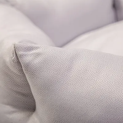 Gros plan d’un coussin en tissu gris clair à motif géométrique. Vue détaillée de la texture.