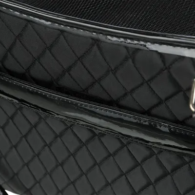 Nahaufnahme einer schwarzen Tasche mit gestepptem Stoff und glänzenden Details. Sichtbares Netzmaterial oben und Metallclip an der Seite.