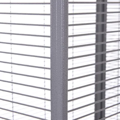 Dettaglio angolo di una gabbia in metallo con sbarre orizzontali grigie ravvicinate, struttura robusta visibile.