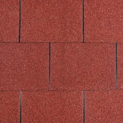 Close-up van rode dakshingles met korrelige textuur en rechthoekig patroon.