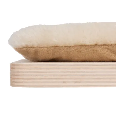 Nahaufnahme eines beigen Kissens mit weicher, cremefarbener Oberfläche auf einer Holzplatte.