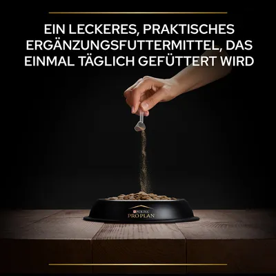 Main en train de saupoudrer un complément alimentaire sur des croquettes dans une gamelle Purina Pro Plan. Texte en allemand : Ein leckeres, praktisches Ergänzungsfuttermittel, das einmal täglich gefüttert wird.