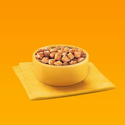 Bowl filled with chunks of wet pet food in gravy, placed on a folded yellow napkin against an orange background.