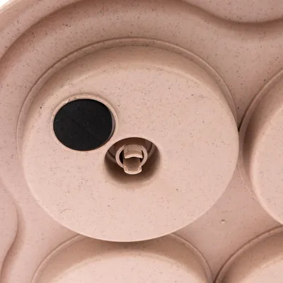 Close-up of a beige toy with rotating elements and a black felt dot. Suitable for interactive play or food hiding.
